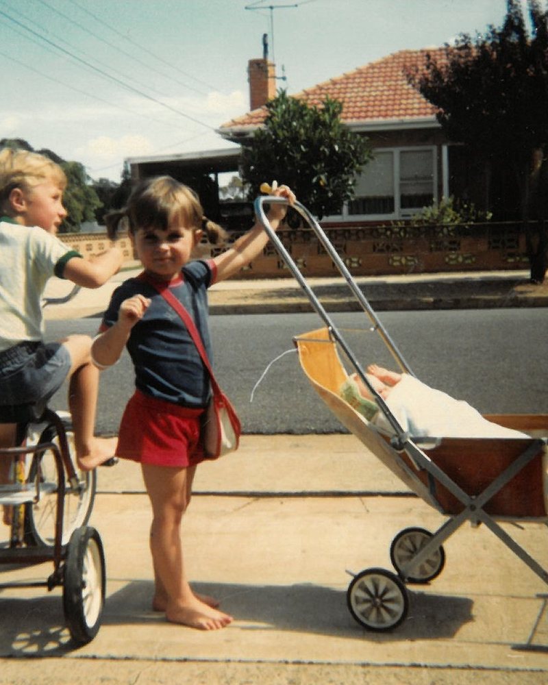 Katherine and her brother Jack — Jack on his bike, Katherine with a pram
